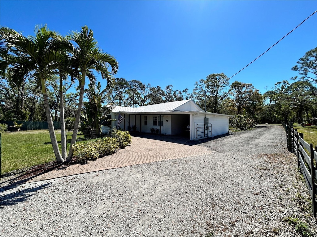 view of front of house with metal roof, decorative driveway, a front lawn, and fence