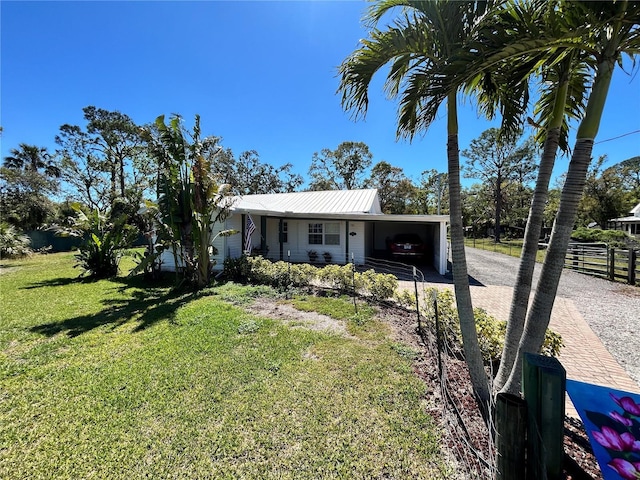 view of front facade with a front lawn, decorative driveway, fence, metal roof, and an attached carport