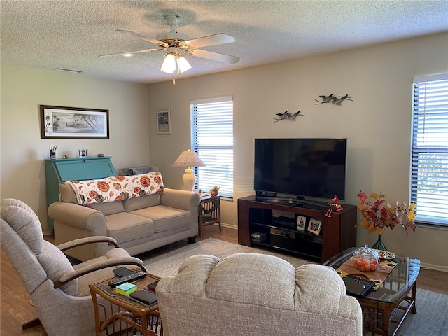 living area featuring ceiling fan, a textured ceiling, wood finished floors, and baseboards