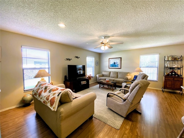 living area featuring ceiling fan, a textured ceiling, baseboards, and wood finished floors