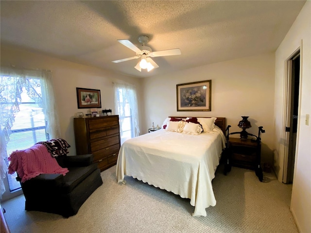 bedroom with ceiling fan, a textured ceiling, and light colored carpet