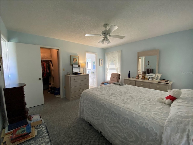 bedroom featuring a walk in closet, a closet, a ceiling fan, light carpet, and a textured ceiling