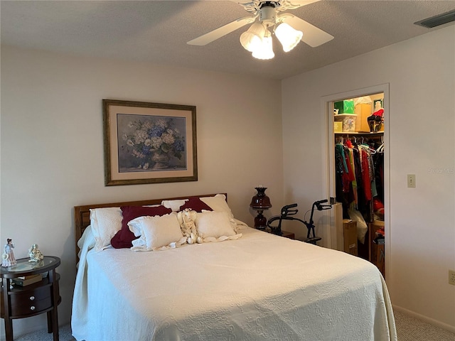 carpeted bedroom with a walk in closet, a closet, visible vents, a ceiling fan, and baseboards