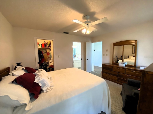 bedroom featuring visible vents, a ceiling fan, a closet, carpet, and a walk in closet