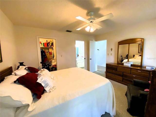 carpeted bedroom with a walk in closet, a closet, visible vents, and ceiling fan