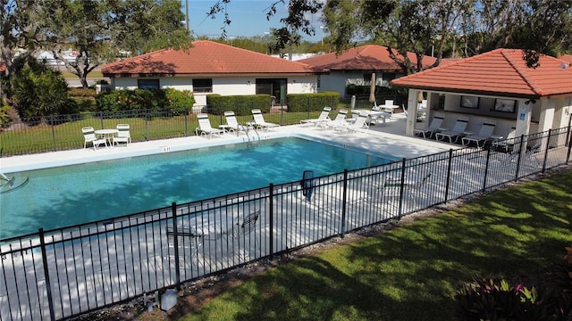 pool with a patio area, fence, and a lawn