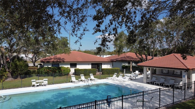 community pool with a patio area and fence