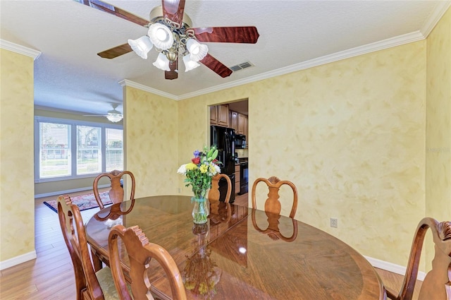 dining space with baseboards, visible vents, a textured ceiling, crown molding, and light wood-style floors