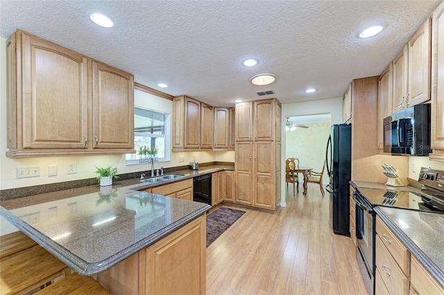 kitchen featuring a sink, black appliances, light wood-type flooring, a peninsula, and a kitchen bar