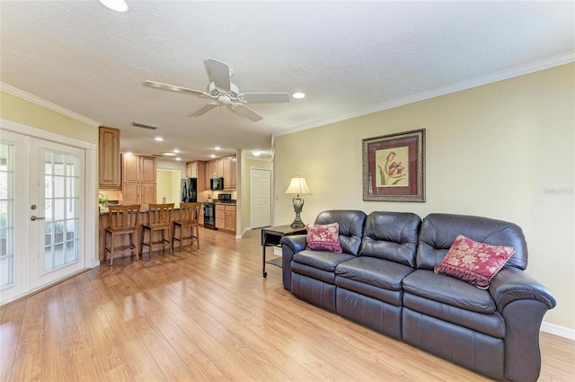 living area featuring visible vents, crown molding, a textured ceiling, and light wood finished floors