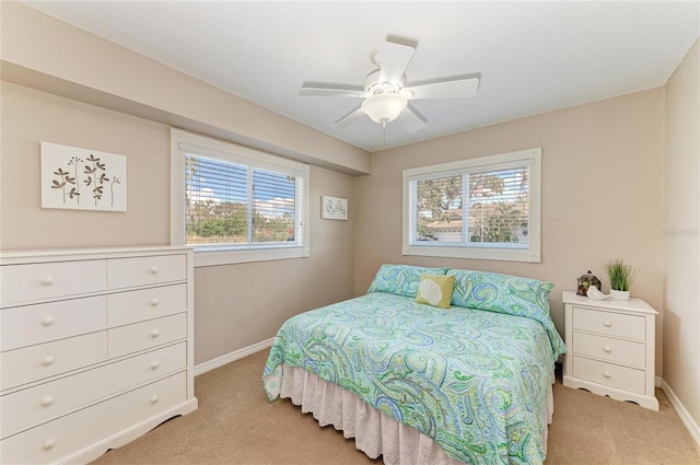 bedroom with light carpet, ceiling fan, and baseboards