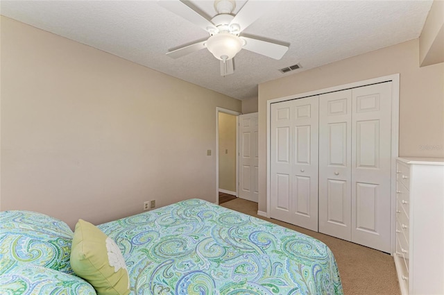 bedroom with visible vents, a ceiling fan, light colored carpet, a textured ceiling, and a closet