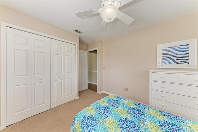 bedroom featuring a textured ceiling, light carpet, a ceiling fan, baseboards, and a closet