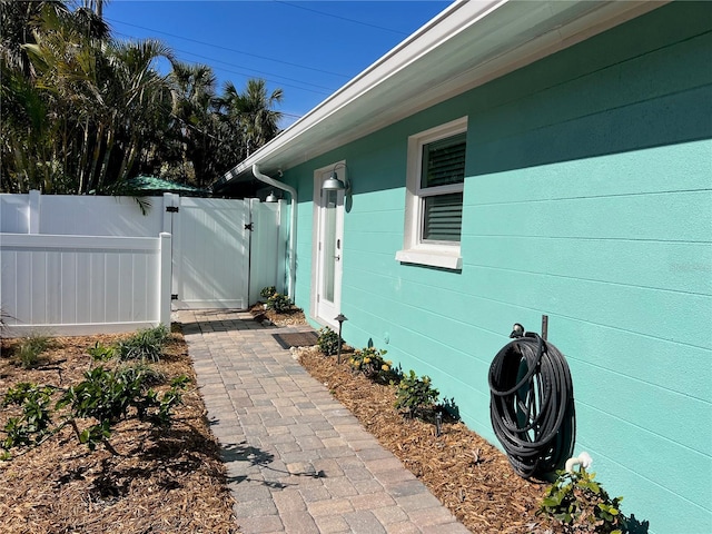 view of side of home with concrete block siding, fence, and a gate