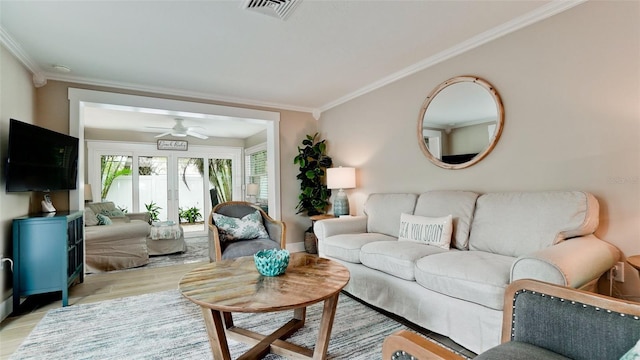 living room featuring light wood finished floors, visible vents, ceiling fan, and ornamental molding
