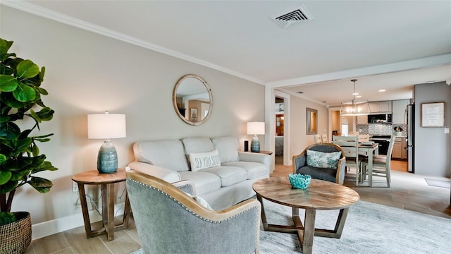 living room featuring crown molding, light wood-style floors, visible vents, and baseboards