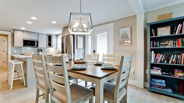 dining room featuring baseboards, light wood finished floors, recessed lighting, ornamental molding, and a notable chandelier