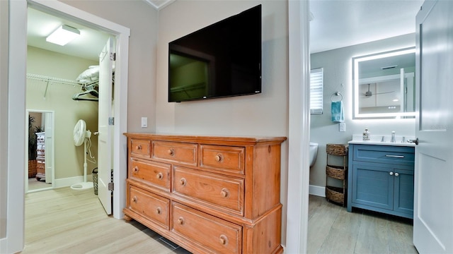 hall featuring a sink, baseboards, and light wood finished floors