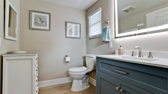 bathroom featuring vanity, wood finished floors, visible vents, baseboards, and toilet