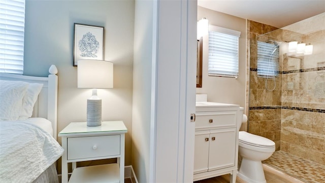 bathroom featuring toilet, tiled shower, and vanity