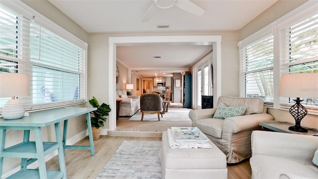 living room with visible vents, light wood-type flooring, and ceiling fan