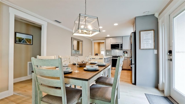 dining space featuring visible vents, a notable chandelier, recessed lighting, crown molding, and light wood finished floors