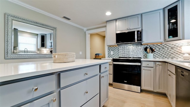 kitchen featuring visible vents, gray cabinets, stainless steel appliances, light countertops, and crown molding