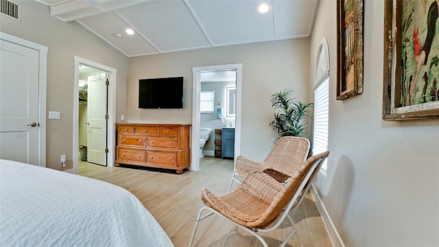 bedroom featuring a walk in closet, visible vents, connected bathroom, light wood finished floors, and vaulted ceiling with beams