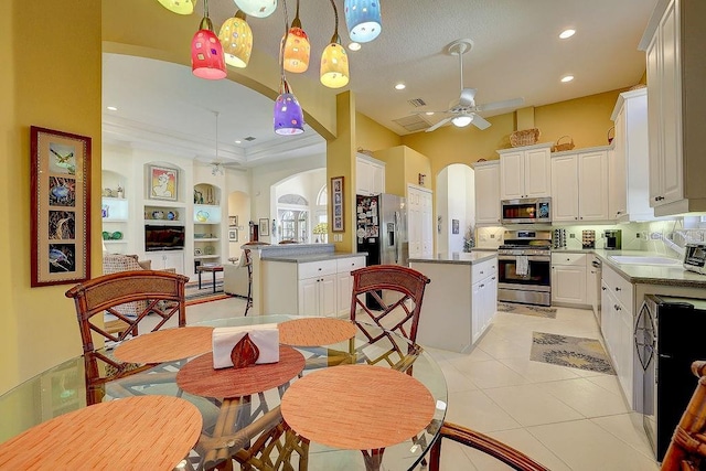 7762 US Open Loop, Lakewood Ranch, FL 34202 - kitchen with appliances with stainless steel finishes, arched walkways, ceiling fan, a kitchen island, and ornamental molding