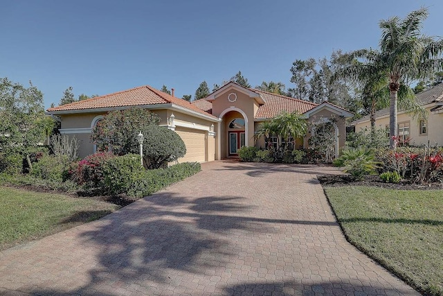 7762 US Open Loop, Lakewood Ranch, FL 34202 - mediterranean / spanish-style home with stucco siding, a garage, a tile roof, decorative driveway, and a front lawn