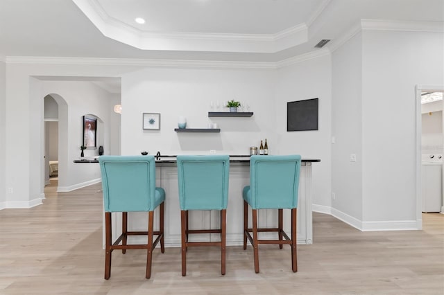 kitchen featuring a breakfast bar, arched walkways, visible vents, and a tray ceiling