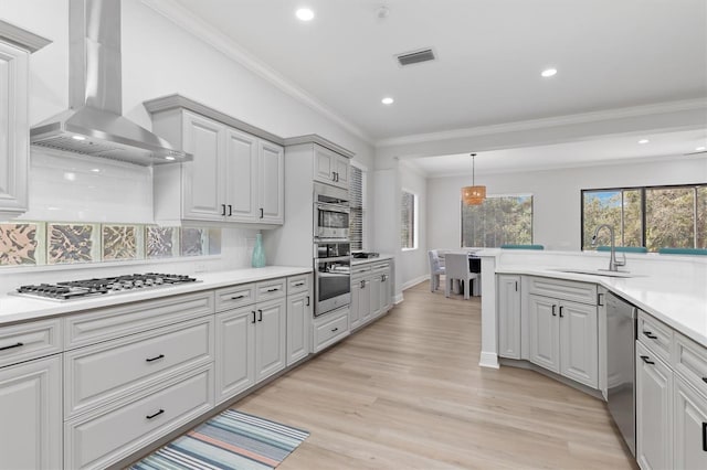 kitchen with visible vents, light wood-style flooring, appliances with stainless steel finishes, a sink, and wall chimney exhaust hood