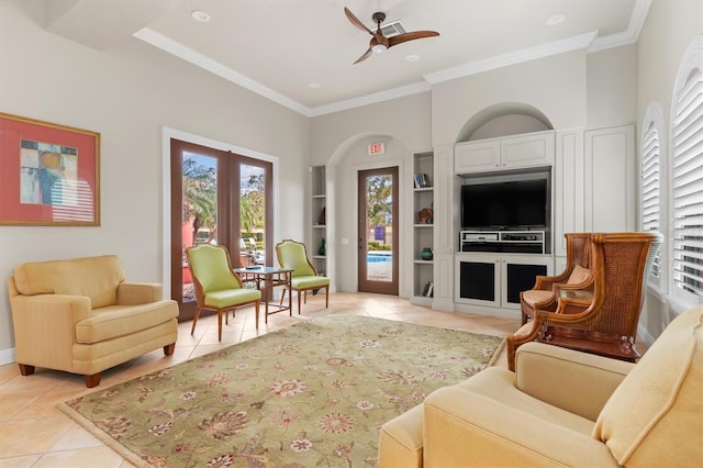 living area with light tile patterned floors, ceiling fan, built in shelves, and crown molding