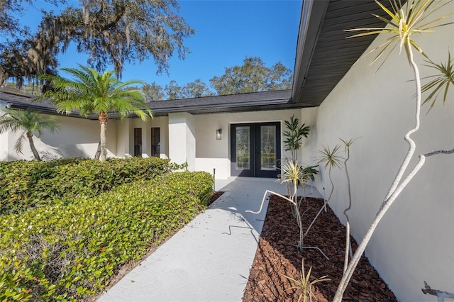 entrance to property featuring french doors and stucco siding