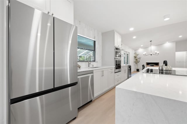 kitchen featuring light wood-style flooring, white cabinetry, stainless steel appliances, and a sink