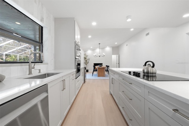 kitchen with visible vents, dishwasher, light wood-style flooring, black electric stovetop, and a sink