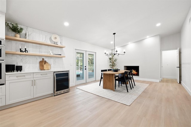 kitchen with light wood-type flooring, wine cooler, light countertops, and french doors