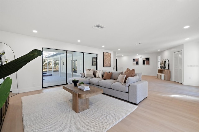 living room with light wood-style flooring, visible vents, baseboards, and recessed lighting