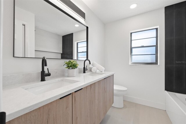 full bathroom with a tub to relax in, a sink, toilet, and double vanity