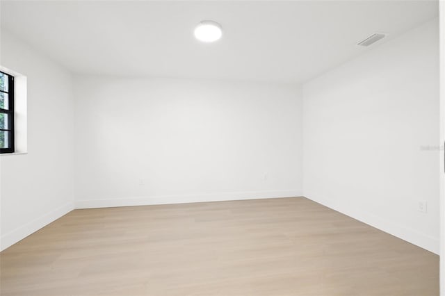 empty room featuring light wood finished floors, baseboards, and visible vents