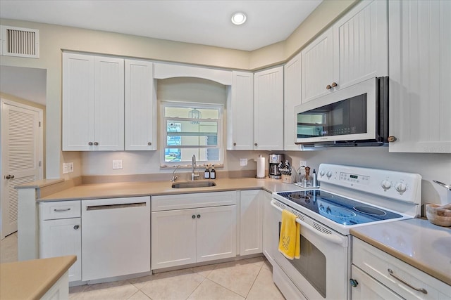 kitchen with light countertops, visible vents, light tile patterned flooring, a sink, and white appliances