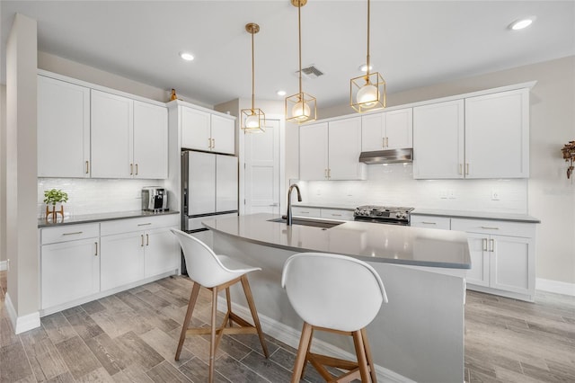 kitchen with stainless steel gas range oven, visible vents, refrigerator, under cabinet range hood, and a sink