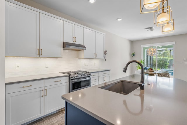 kitchen featuring under cabinet range hood, a sink, visible vents, stainless steel gas range, and tasteful backsplash