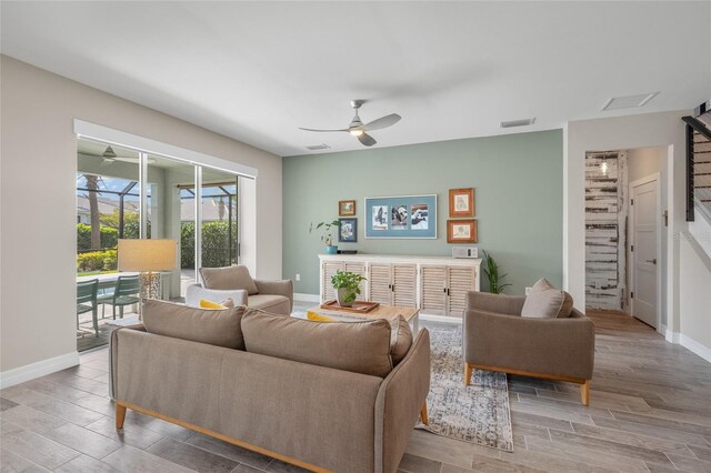 living room with baseboards, wood finished floors, visible vents, and a ceiling fan