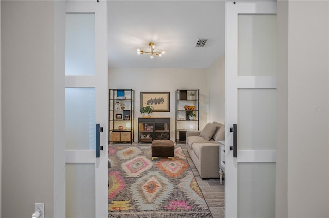 living area with an inviting chandelier, a barn door, and visible vents