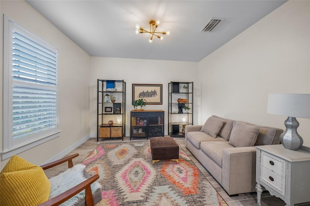 living room featuring light wood-style floors, visible vents, baseboards, and an inviting chandelier