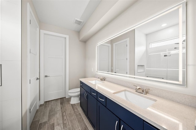 bathroom with toilet, wood finished floors, a sink, and visible vents