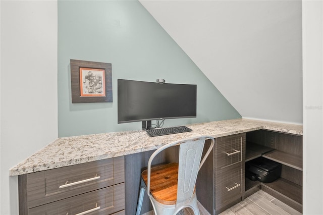 office space featuring light wood-style floors, vaulted ceiling, and built in study area