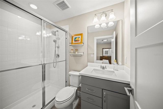 ensuite bathroom featuring visible vents, a shower stall, toilet, and vanity