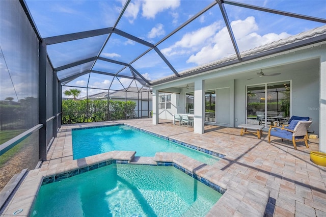 view of pool with a ceiling fan, glass enclosure, a pool with connected hot tub, and a patio area